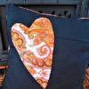 Coussin carré de dimensions 35 X 35 cms coussin noir avec un grand coeur appliqué dans les tons orange Matière du tissu polyester et coton Coussin déhoussable finition portefeuille Intérieur du coussin 100% polyester Conseil de lavage 40°