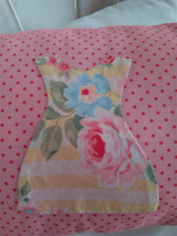 Petit coussin rectangulaire dimensions 26 X 45 cms Le fond du coussin est rose à petits pois Le coussin est agrémenté de 3 petites robes dans un tissu fleuri aux tons roses et jaunes, appliquées à petits points serrés La face arrière du coussin est blanche avec un petit coeur rose brodé main Matière du coussin 100 % coton Intérieur du coussin 100% polyester Conseil de lavage 30°