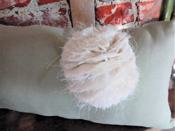 Petit coussin rectangulaire dimensions 43 X 22 cms Coloris uni vert tendre Agrémenté d'un pompon vaporeux écru en polyester Matière du tissu 100% coton Coussin non déhoussable Intérieur du coussin 100% polyester