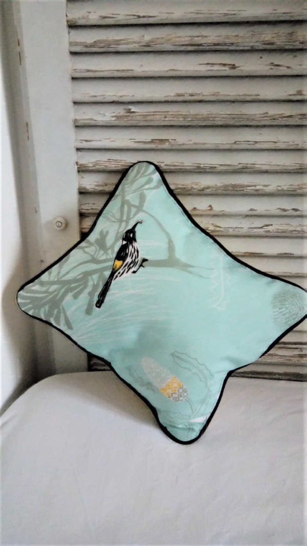 petit coussin de dimensions 28 cms par 34 cms, dans un joli tissu turquoise pâle, coussin gansé d'un passepoil noir, . Une pie sur le coussin a volé un strass dans les boîtes de perles de l'atelier. L'extérieur du coussin est 100% coton et l'intérieur du coussin est 100% polyester. L'envers du cusssin est jaune et ce coussin est déhoussable