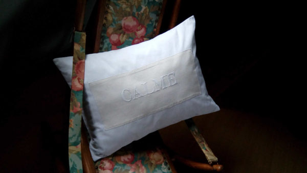 coussin en coton écru de dimensions 4 cms par 64 cms. Mot calme brodé main en majuscules et en blanc. Coussin déhoussable, finition portefeuille;