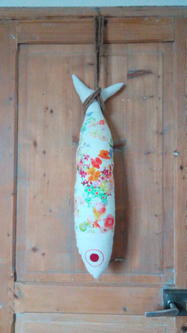 coussin en forme de grand poisson en tissu recyclé , fleurs de couleurs vives sur un fond blanc, longueur du coussin 72 cms, largeur du coussin 17 cms