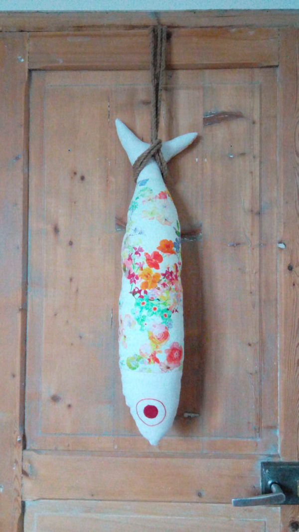 coussin en forme de grand poisson en tissu recyclé , fleurs de couleurs vives sur un fond blanc, longueur du coussin 72 cms, largeur du coussin 17 cms